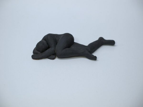 Escultura masculina de cerámica con la figura de un hombre tumbado