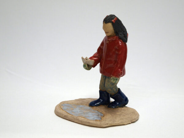 Escultura cerámica de una niña jugando
